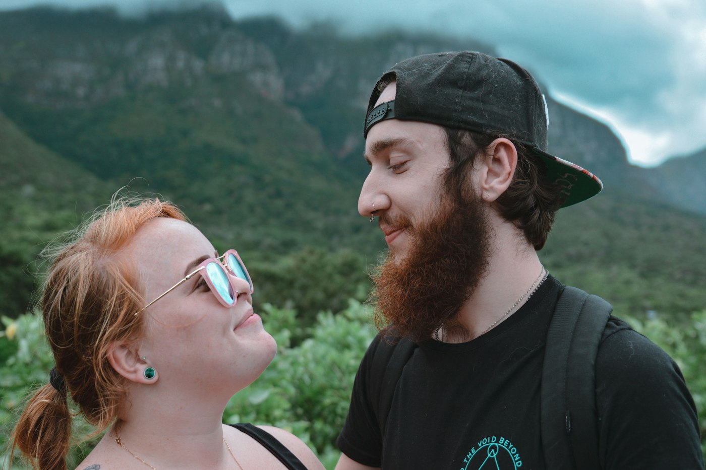 A couple smiling at each other with a mountain view