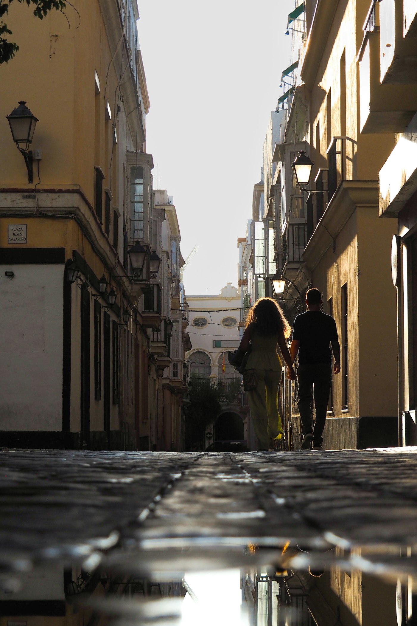 A couple holding hands on a cobblestone street